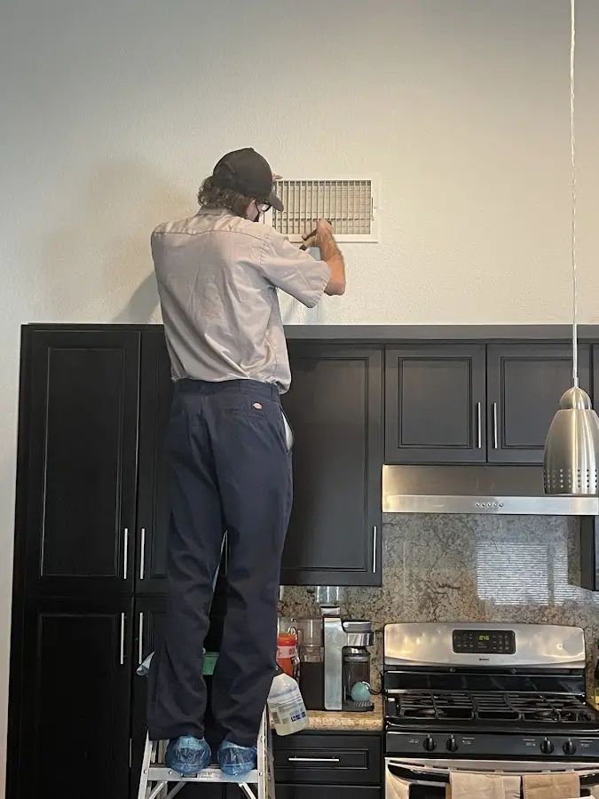 Technician inspecting an air vent during HVAC service in Hobart